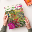 Schräg gehaltene Gartenzeitschrift „GartenFlora“, Ausgabe September 2026, mit grünem und pinkem Titel sowie dem Untertitel „gärtnern, erleben und genießen“. Das Cover zeigt einen blühenden Garten und eine weibliche Person im kleinen Foto; sichtbar sind außerdem die Texte „Magischer Spätsommer in Burgunderrot“, „So werden Sommerblumen gezüchtet“ und „Mini-Kiwis für den Garten“, gehalten von zwei Händen auf weißer Fläche.
