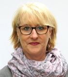 Frau mit blonden Haaren, Brille und gemustertem Schal.