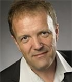 Porträt eines lächelnden Mannes mit kurzen, hellbraunen Haaren.