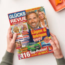 Aufgeschlagenes Magazin „GLÜCKS REVUE“ mit rotem und blauem Titelbereich, gelbem Schriftzug „EXTRA-RÄTSELHEFT“ und „Ratespaß“. Das Cover zeigt Jürgen Klopp und eine blonde Frau sowie Themen zu „Lügen & Intrigen“, Rezepten, Diabetes, Helene Fischer, einem grünen Auto und Spartipps; zwei Hände halten das Heft vor weißem Hintergrund, oben rechts liegt ein orangefarbenes Tablett.