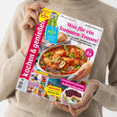 Person im beigen Strickpullover hält eine schräg fotografierte Zeitschrift mit dem Titel „Kochen & genießen“. Das Cover zeigt ein Tomatengericht mit Basilikum, die Texte „Was für ein Tomaten-Traum!“, „Schnell & köstlich: Airfryer-Rezepte“, „Der Pool ruft“ und „Einfach frisch & fruchtig: Sommerkuchen“ sowie weitere Rezeptbilder.