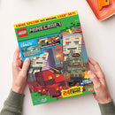 Aufgeschlagenes, rechteckiges LEGO-Minecraft-Magazin mit grünem, blauem und farbig illustriertem Cover, gehalten von zwei Händen über weißem Hintergrund; oben rechts liegt teilweise ein orangefarbenes Tablett. Sichtbare Texte: „COMIC SPECIAL MIT ORIGINAL LEGO SET!“, „LEGO“, „MINECRAFT“, „ZWEI TOLLE COMICS!“, „MUTPROBE IM NETHER!“, „COOL ACTION!“, „24 SEITEN ACTION“, „Mojang Studios“ und „Blue Ocean“.