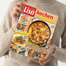 Person in beigefarbenem Strickpullover hält ein schräg dargestelltes Koch- und Backmagazin mit dem Titel „Lisa kochen & backen“. Das Cover zeigt ein Pfannengericht mit Hackbällchen, mehrere kleinere Speisenfotos sowie die Texte „Einfache Rezepte, die alle begeistern“, „Extra: 16 Seiten Spar-Rezepte“ und „Schnell, lecker, neu: 30-Minuten-Hits“; das Geschlecht der Person ist nicht erkennbar.