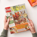 Titelbild der Zeitschrift „Lisa Wohnen & Dekorieren“, Ausgabe Oktober 2026, mit orangefarbenen Herbstblumen, Kürbissen und einem geflochtenen Korb vor einer Wohnszene. Sichtbare Texte: „Dekolust im Herbst“, „Wohlfühl-Mix Orange und Naturtöne“ und „58 kreative Herbst-Ideen“; das Magazin wird von zwei Händen gehalten.