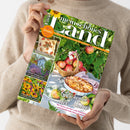 Aufsicht auf eine Person in beigem Strickpullover, die ein schräg gehaltenes Magazin mit dem Titel „mein schönes Land“ hält. Das Cover zeigt Sonnenblumen, grüne Blätter, einen Apfelkorb, Apfelkuchen und Gartenbilder; Texte: „30 Seiten kreativ durch den Herbst“, „Gutes bewahren · Schönes entdecken · September“, „Geschenke der Natur“ sowie „Oktober 2026“.