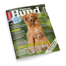 Schräg fotografiertes Magazincover „Partner Hund“ mit grünem Hintergrund, einem großen braunen Hund und einem kleineren braunen Welpen mit weißer Brustzeichnung. Sichtbare Texte: „Kleine Hunde erziehen“, „Fakten-Check Nass- oder Trockenfutter“, „Osteopathie“, „Schleppleine“ und „Liebevolle Klarheit – Leidenschaft Vertrauen“; links ist ein männlicher Mensch abgebildet.