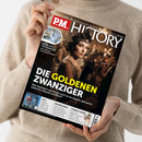 Person im beigefarbenen Strickpullover hält ein schräg fotografiertes Magazin mit dem Titel „P.M. HISTORY“ und der Aufschrift „Europas größtes Monatsmagazin für Geschichte“. Das Cover zeigt eine Frau mit Stirnband und Perlenkette in einer festlich beleuchteten Szene sowie die Schlagzeile „DIE GOLDENEN ZWANZIGER“ und den Text „Was fasziniert uns heute noch so an diesem Jahrzehnt zwischen Rausch und Ruin?“.