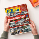 Schräg gehaltenes Magazin „pro mobil“ mit rotem und gelbem Cover, das von zwei Händen einer nicht näher bestimmbaren Person gehalten wird. Sichtbare Texte: „Über 50 Camping- und Stellplätze“, „Großes Caravan-Salon-Spezial“, „Neuheiten 2027“, „75 neue Modelle“, „Lithium-Akkus im Test“ und „Deutschland & Schweiz“; abgebildet sind mehrere weiße, graue und schwarze Wohnmobile.