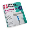 Schräg fotografiertes Magazincover „Stiftung Warentest“ mit türkis-weißem Hintergrund, pinkem Logo und großem Titel „Wandfarben“. Abgebildet ist eine Farbrolle mit weißer Struktur und blauem Griff; sichtbare Texte nennen außerdem „Auch günstige decken gut“, „Smartphone-Preise“, „Kinderwagen“, „Geschirrspültabs“, „Volumenshampoos“, „Kirschjoghurts“, „Kühl-Gefrier-Kombis“, „Drucker“ und „Diagnose per KI“.