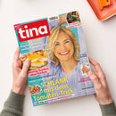 Auf weißer Fläche halten zwei Hände eine schräg liegende Zeitschrift „tina“ mit rotem Titelkasten und dem Bild einer blonden Frau. Das Cover zeigt unter anderem die Texte „Kopfschmerzen einfach wegdrücken“, „Cremige Kuchen ohne Backen“, „SCHLANK mit dem Tomaten-Trick“, „Die schönsten Camping-Trends“ und „Lifting mit Rouge sofort frischer aussehen“; oben rechts liegt ein orangefarbenes Tablett.