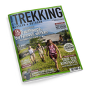 Schräg dargestelltes Magazincover „TREKKING – Wandern & Outdoor“ mit grünem Rand auf schwarzem Hintergrund. Das Titelbild zeigt zwei weibliche und eine männliche Person mit Rucksäcken und Wanderstöcken auf einer alpinen Wiese vor Berghütte und Bergen; lesbare Texte: „14 Traumwege, die Fernweh wecken – Von Italien bis Irland“, „Trentino“, „Tour der Kontraste“, „Irlands Südwesten“, „Kat Walk“ und „Sommerbekleidung“.