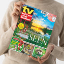 Weibliche Person im beigen Strickpullover hält ein schräg aufgenommenes Magazin mit dem Titel „TV Hören und Sehen“. Das Cover zeigt einen See bei Sonnenuntergang, Blumen und die Texte „Deutschlands schönste Seen“, „Die Heimat genießen“, „Der große Bundesliga-Planer“, „Wandern“ sowie „Kleiner Freund im Garten“ mit einem Igelbild.