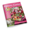 Schräg fotografierte Zeitschrift „Wohnen & Garten“ mit pinkem Cover und dem Text „Die schönsten Ideen für drinnen und draußen“. Abgebildet sind ein Blumenarrangement in einem grünen Topf, Äpfel, Kürbissuppe, ein Landhaus sowie eine von hinten sichtbare Person im Garten; weitere Texte lauten „Blüten-Finale im Rosé“, „Jetzt genießen: Suppen & Eintöpfe“, „Garten & Pflanzen“ und „Dekorieren“.