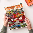 Schräg von oben fotografierte Ausgabe des Magazins „YOUNGTIMER“ mit weißem Papiercover, orangefarbener Titelzeile, roten Flächen und mehreren Fahrzeugbildern, darunter Chevrolet Camaro, Audi 100 CS, SsangYong Actyon, Ford Focus ST, Mercedes, Audi RS2, Volvo und VW Multivan. Aufgedruckt sind „MotorKlassik“, „DIE KULT-KLASSIKER DER 70ER, 80ER UND 90ER“, „JULI/AUGUST 2026“ und „HIGH FIVE!“; zwei nicht näher zuordenbare Hände halten das Magazin vor weißem Hintergrund.